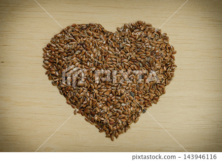 Raw flax seeds linseed heart shaped on wooden table Raw flax seeds linseed heart shaped on wooden table 143946116