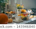 vintage teacup surrounded by small pumpkins on lace tablecloth, cozy autumn harvest decoration featuring seasonal gourds and floral bokeh 143946840