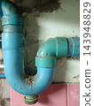Pipe plumbing drain trap with blue curved fitting against stained wall 143948829