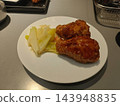 Glazed chicken drumstick with cabbage on white plate at dining table 143948835
