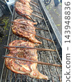 Grilled poultry on charcoal barbecue with browned skin over outdoor metal grate 143948836