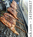 Grilled chicken on bamboo skewer over charcoal with browned skin 143948837
