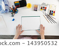 Woman preparing watercolor paper at a bright desk for mindful, screenless painting 143950532