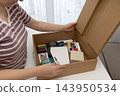 Woman opens a box of art supplies to revive a long neglected analog hobby at home in daylight 143950534