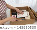 Woman sorting art materials at a white table, returning to an analog art hobby 143950535