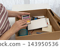 Woman selecting pastel sticks from a cardboard box on a table for a relaxing analog art session 143950536