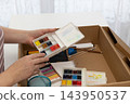 Woman opens watercolor paint case in a calm indoor art space, rediscovering analog painting 143950537