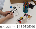 Woman selecting watercolor brushes at a bright white art desk for a relaxing offline hobby 143950540