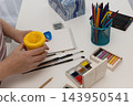 Woman preparing painting supplies at a bright white art desk, calm creative hobby 143950541