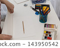 Woman Begins Painting on Blank Paper in a Bright Home Studio, Embracing Analog Art 143950542