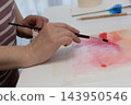 Woman painting with watercolors at a home studio desk, embracing screen free creative flow 143950546