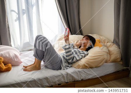 一名婦女在床上的看一個智能手機 143951731