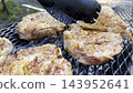 Male hands turning with plastic tongs pork steaks on home grill at sunny summer day. The focus is on the careful flipping and the rich texture of the meat as they cook evenly over the fire 143952641