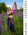 Vibrant dancer in colorful outfit showcases traditional moves among blooming lavender flowers on a sunny day 143952925