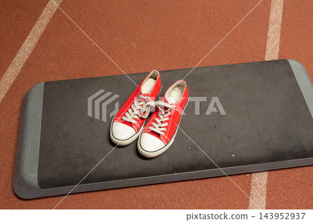Red sneakers on gym mat in sports facility during training session Red sneakers on gym mat in sports facility during training session 143952937