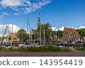 Wide angle coastal digital publication of town hall clock tower harbor sailboats traditional Dutch brick houses blue sky Veere Zeeland Netherlands European travel maritime heritage commercial 143954419