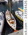 High angle vertical perspective classic wooden sailboat moored harbour marina deck posts yachts ropes clear water Veere Zeeland Netherlands European travel commercial 143954426