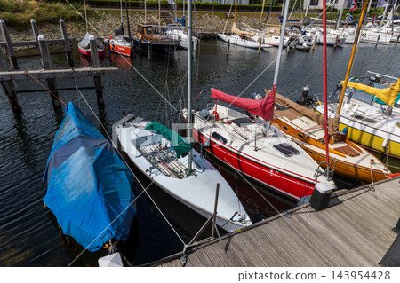 High angle horizontal perspective sailboat harbor marina wooden pier boardwalk moored yachts colorful hulls ropes clear water Veere Zeeland Netherlands European travel commercial High angle horizontal perspective sailboat harbor marina wooden pier boardwalk moored yachts colorful hulls ropes clear water Veere Zeeland Netherlands European travel commercial 143954428
