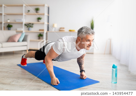 Sport during quarantine. Mature man doing push-up exercises on fists, training in living room at home, free space. Sport exercises, active lifestyle during quarantine Sport during quarantine. Mature man doing push-up exercises on fists, training in living room at home, free space. Sport exercises, active lifestyle during quarantine 143954477