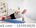 Strong mature man working out at home, making plank and showing thumb up, smiling to camera in living room interior, training on yoga man, free space 143954826