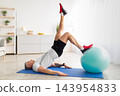 Active mature man exercising with ball, doing abs exercises on mat in living room interior, free space. Senior man leading healthy lifestyle, working out during covid-19 isolation 143954833