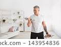 Domestic training concept. Sporty mature man exercising with dumbbells at home, working out his biceps, leading active lifestyle, pumping muscles, free space 143954836