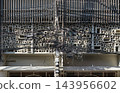Wide architectural shot featuring a dense, horizontal tangle of overhead telecommunication cables and power lines juxtaposed against a modern concrete breeze block building facade with vertical 143956602