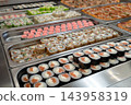 Sushi roll japanese food in grocery store, buffet, or food court. Buying sushi rolls in a store. Japanese food. Various types of sushi rolls on display at a grocery store. 143958319