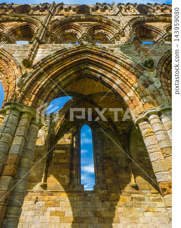Gothic arches made of weathered sandstone against a blue sky: Ruins of Whitby Abbey (Whitby, England) 143959080