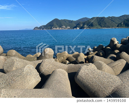 防波堤外，碧海藍天，青山綿延。陽光明媚的海岸風光。橫幅照片。 143959108