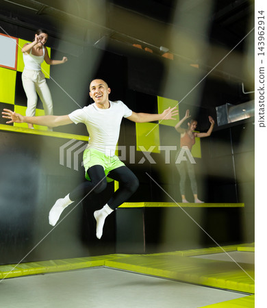 Fitness, fun, leisure and sport activity concept - happy man jumping on trampoline indoors Fitness, fun, leisure and sport activity concept - happy man jumping on trampoline indoors 143962914