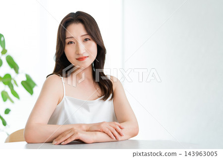 A woman's natural beauty shines through as she smiles in a bright setting. A woman's natural beauty shines through as she smiles in a bright setting. 143963005