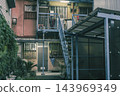 A retro apartment building with an outdoor steel staircase and an aged, deteriorated exterior. 143969349
