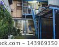A retro apartment building with an outdoor steel staircase and an aged, deteriorated exterior. 143969350
