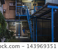 A retro apartment building with an outdoor steel staircase and an aged, deteriorated exterior. 143969351