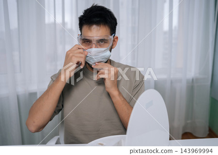 Portrait of technician male in protective glasses and mask preparing for robot vacuum cleaner maintenance, prioritizing home safety, appliance care and cleaning technology. 143969994