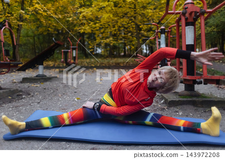 Mature woman practicing yoga and stretching outdoors in an autumn park. Active senior enjoying healthy aging, fitness, and vitality through outdoor workout and mindfulness. Mature woman practicing yoga and stretching outdoors in an autumn park. Active senior enjoying healthy aging, fitness, and vitality through outdoor workout and mindfulness. 143972208