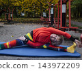 Mature woman practicing yoga and stretching outdoors in an autumn park. Active senior enjoying healthy aging, fitness, and vitality through outdoor workout and mindfulness. 143972209
