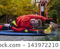 Mature woman practicing yoga and stretching outdoors in an autumn park. Active senior enjoying healthy aging, fitness, and vitality through outdoor workout and mindfulness. 143972210