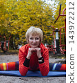 Mature woman practicing yoga and stretching outdoors in an autumn park. Active senior enjoying healthy aging, fitness, and vitality through outdoor workout and mindfulness. 143972212