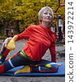 Mature woman practicing yoga and stretching outdoors in an autumn park. Active senior enjoying healthy aging, fitness, and vitality through outdoor workout and mindfulness. 143972214