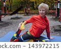Mature woman practicing yoga and stretching outdoors in an autumn park. Active senior enjoying healthy aging, fitness, and vitality through outdoor workout and mindfulness. 143972215