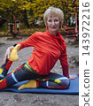 Mature woman practicing yoga and stretching outdoors in an autumn park. Active senior enjoying healthy aging, fitness, and vitality through outdoor workout and mindfulness. 143972216