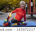 Mature woman practicing yoga and stretching outdoors in an autumn park. Active senior enjoying healthy aging, fitness, and vitality through outdoor workout and mindfulness. 143972217