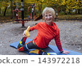 Mature woman practicing yoga and stretching outdoors in an autumn park. Active senior enjoying healthy aging, fitness, and vitality through outdoor workout and mindfulness. 143972218