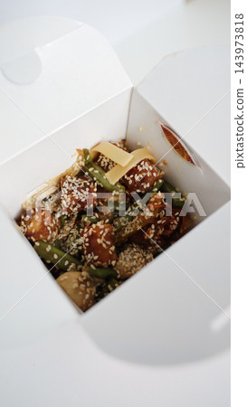 Asian takeaway meal with green beans, tofu, sesame seeds, and noodles in a white cardboard box for quick lunch Asian takeaway meal with green beans, tofu, sesame seeds, and noodles in a white cardboard box for quick lunch 143973818