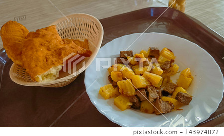 Traditional Altai kurdak fried horsemeat with potato on plate beside bread basket on tray 143974072