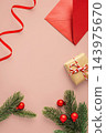 Christmas background, flat lay composition with gift box, red envelope, and pine branches on a pink background 143975670