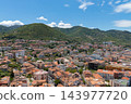 Aerial panorama hillside town beneath lush green mountains clear summer day 143977720