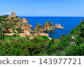 Sunny Mediterranean bay sea stacks coastal greenery hills and historic stone watchtower 143977721
